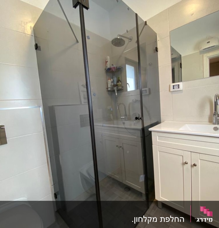 מקלחון זכוכית עם ראש מקלחת ומדף מוצרים